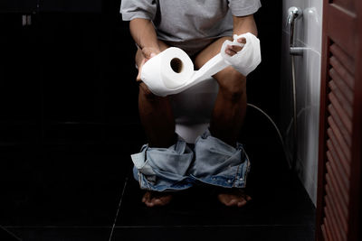 Low section of man holding coffee while sitting on floor at home