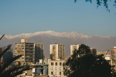 Buildings in city against clear blue sky