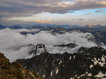 Scenic view of snowcapped mountains and cable car against sky