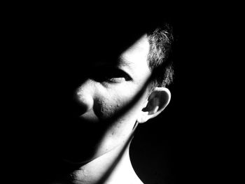 Close-up portrait of young woman over black background