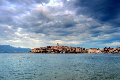 Buildings by sea against sky