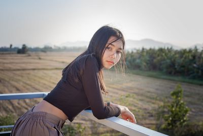 Close-up portrait of young beautiful women standing on wooden stairs with rural screen on background