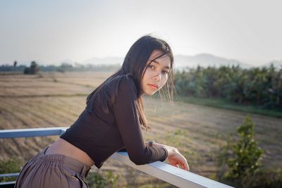 Young woman wearing sunglasses on field against sky