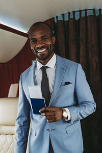 Happy businessman with passport standing in private jet