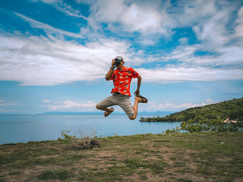 Full length of man jumping against lake