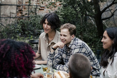 Friends talking with each other during social gathering in back yard