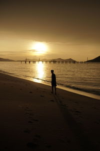 Silhouette man on beach against sky during sunset