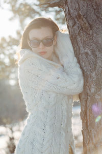 Portrait of woman with sunglasses against trees during winter