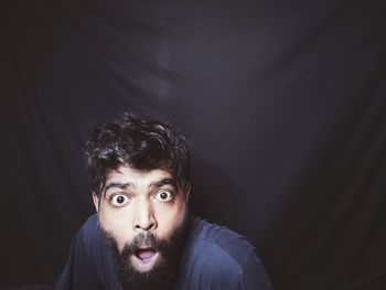 Portrait of young man against black background