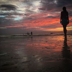 Man standing on beach against sky during sunset