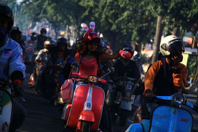 Rear view of people riding motorcycle on street