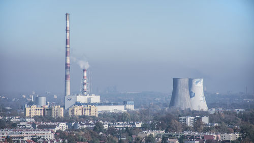 Smoke emitting from factory against sky