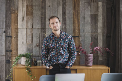 Portrait of confident businessman standing with hands in pockets against wood paneling in portable office truck