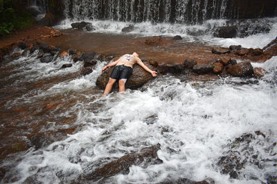 Boy sitting on waterfall