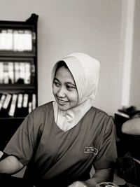 Woman wearing hijab while looking away at home