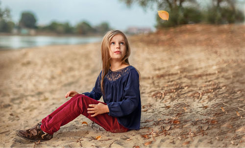 Portrait of young woman sitting on land