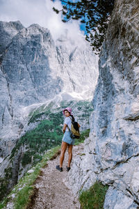 Rear view of woman standing on rock by mountain