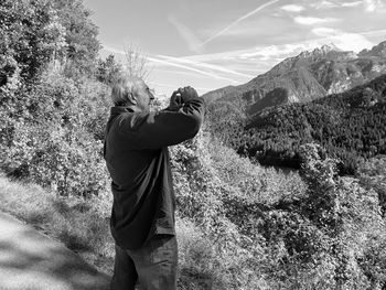 Senior man photographing mountains through mobile phone