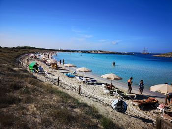 People at beach against blue sky