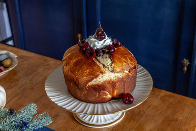 Panettone bread with cherries and whipped cream on a holiday table at christmas.