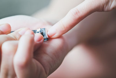 Cropped hands of woman cutting nails with clipper