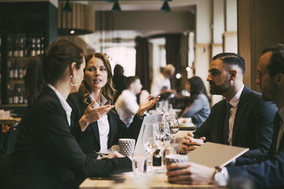 Female entrepreneur discussing with colleagues in restaurant