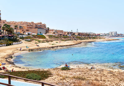 Scenic view of beach and buildings against clear sky