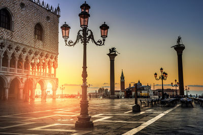 Street lights in city against sky during sunset