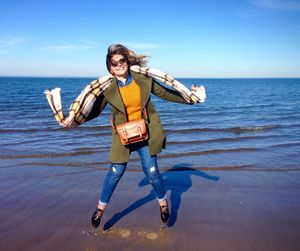 Portrait of smiling young woman jumping at beach