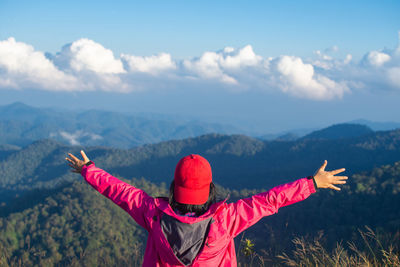 Rear view of woman with arms outstretched standing against mountains