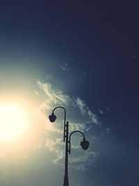 Low angle view of silhouette street light against bright sky