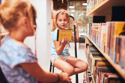 Schoolgirls looking for audio books in school library. students choosing books. elementary education
