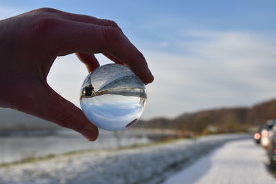 Close-up of hand holding water against sky