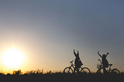 Silhouette of bicycle on field against sky at sunset