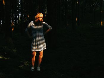 Full length of young woman standing in forest