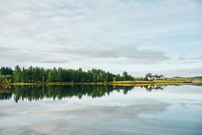 Valley of green fields and trees with house on lake shore