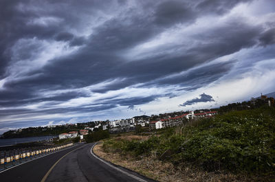 Road in city against storm clouds