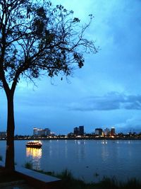 City by river against sky at dusk