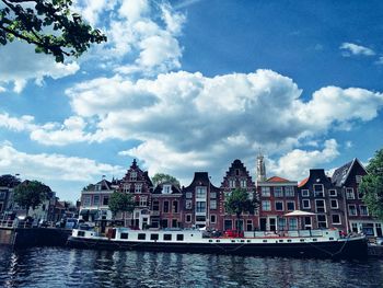 Buildings by river against sky in city