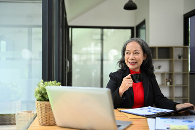 Businesswoman using laptop while sitting on table