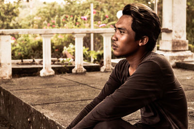 Young man looking away while sitting on staircase