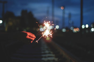 Close-up of hands holding illuminated sparklers at night