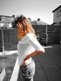 Rear view of woman standing on road against buildings