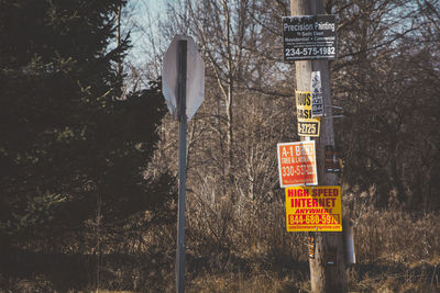 Road sign by trees against sky