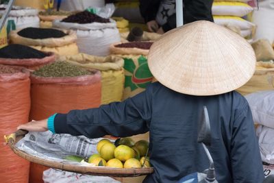 Rear view of man and fruits for sale at market stall