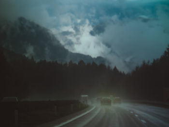 Road amidst trees against sky at dusk