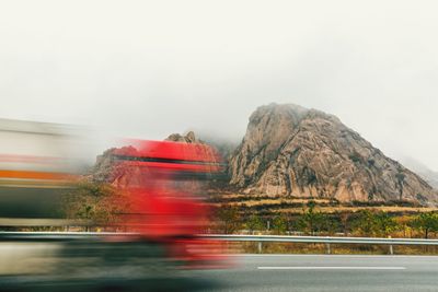 Blurred motion of road by mountain against clear sky