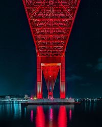 Illuminated bridge over river against sky at night