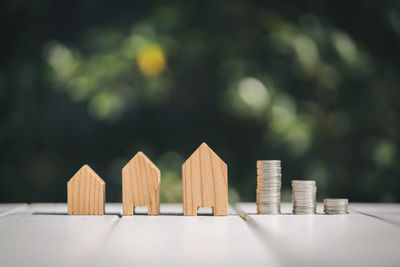 Close-up of wooden model homes and stacked coins on table