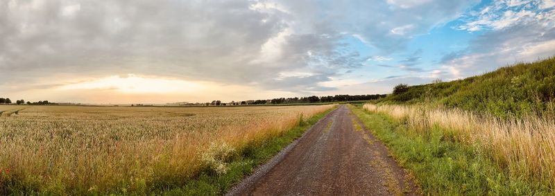 Road amidst field against sky